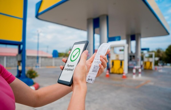 Security and Efficiency with Gas Deck’s Digital Payment System A Person Holding a Smartphone Displaying a "Payment Completed" Confirmation While Holding a Printed Receipt at a Gas Station