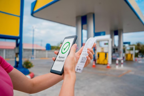 Advanced Secure Payment Systems for Your Business A Customer at a Gas Station Holding a Phone with a "Payment Completed" Screen and a Printed Receipt