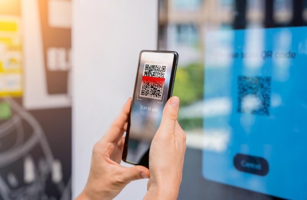 A Person Scans a QR Code on a Screen Using a Smartphone to Make a Payment
