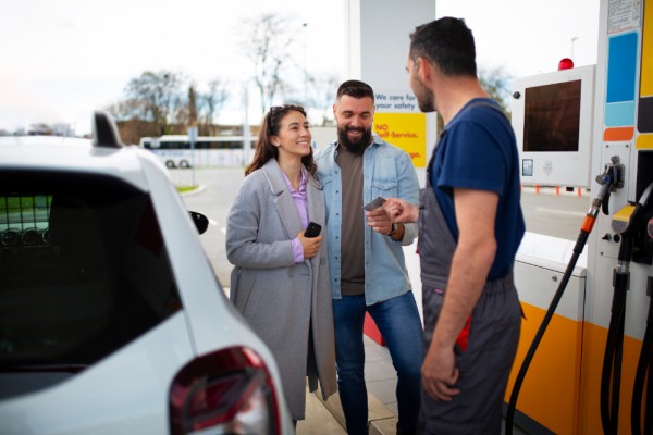 Increase Customer Retention with a Rewarding Experience A Smiling Couple Interacting with a Gas Station Attendant at the Fuel Pump