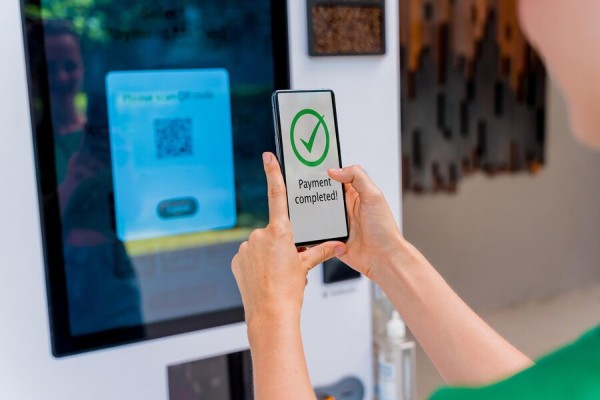 Instant Money Transfer With Bank Account Payments A Person Using a Smartphone to Complete a Digital Payment at a Self-Service Kiosk