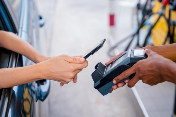 Pay Securely with Multiple Payment Options A Customer Making a Contactless Payment Using a Smartphone at a Gas Station Drive-Through